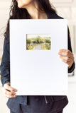 woman holding a landscape watercolor painting on a large mat