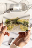 hands holding a loose watercolor landscape painting