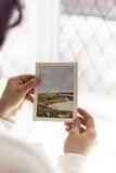 woman holding a landscape acrylic painting on a large mat