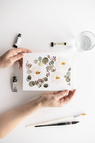 Flavia Bennard hands holding a white watercolor bouquet painting