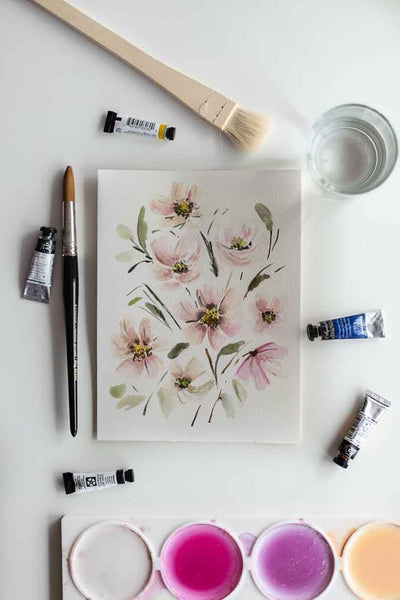 soft watercolor flower bouquet painting on a table with tools