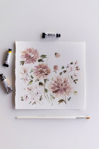 square watercolor flowers painting next to brush and paint tubes