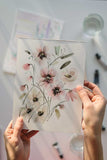 hands holding a loose watercolor flowers painting Flavia Bennard