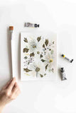 white watercolor flowers bouquet next to brush and paint tubes Flavia Bennard
