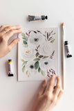 hands holding a loose watercolor flowers painting