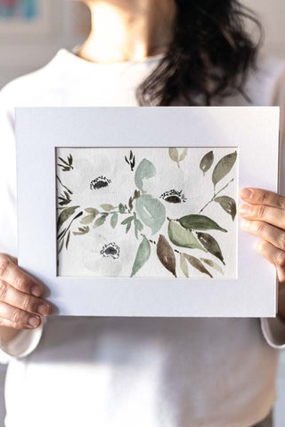 woman holding a painting of white anemones flowers