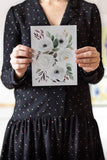 woman holding a white watercolor flowers painting Flavia Bennard