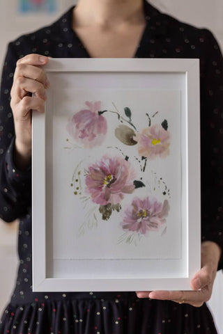 woman holding a watercolor flowers painting on a white frame